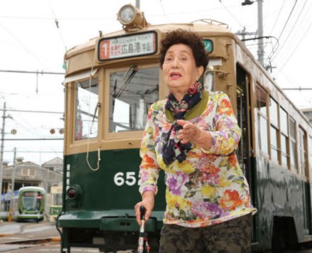 Satako Oka, senare Satako Sasaguchi, framför spårvagn 652.